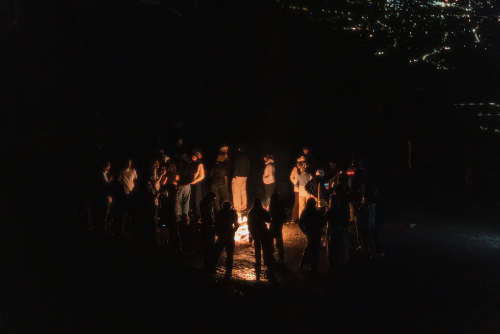 Guests gathered around a bonfire under a night sky