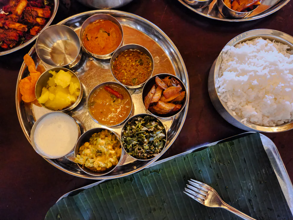 South Indian thali served on a steel plate with rice and curries
